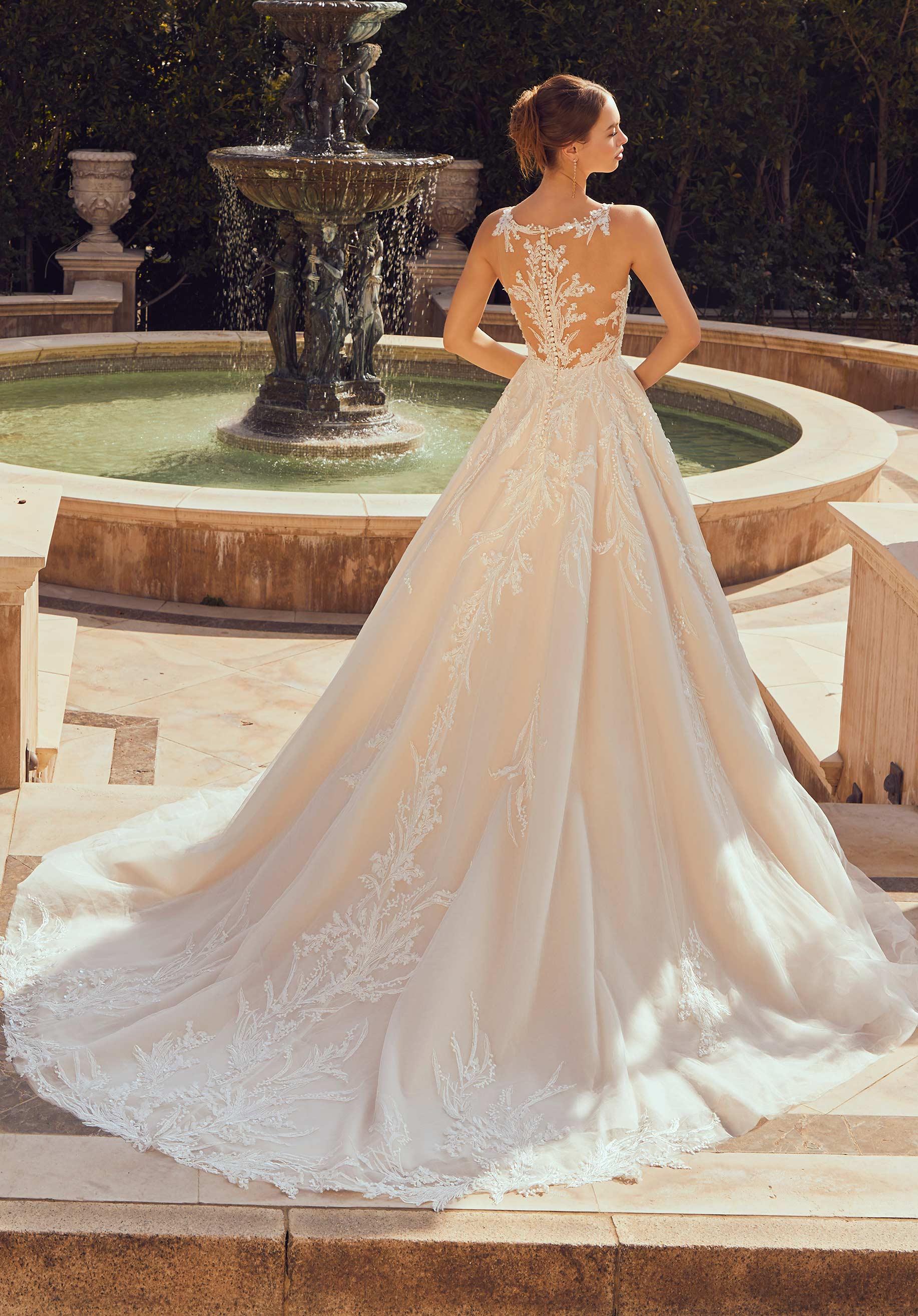 Woman in a white wedding dress standing in front of a fountain