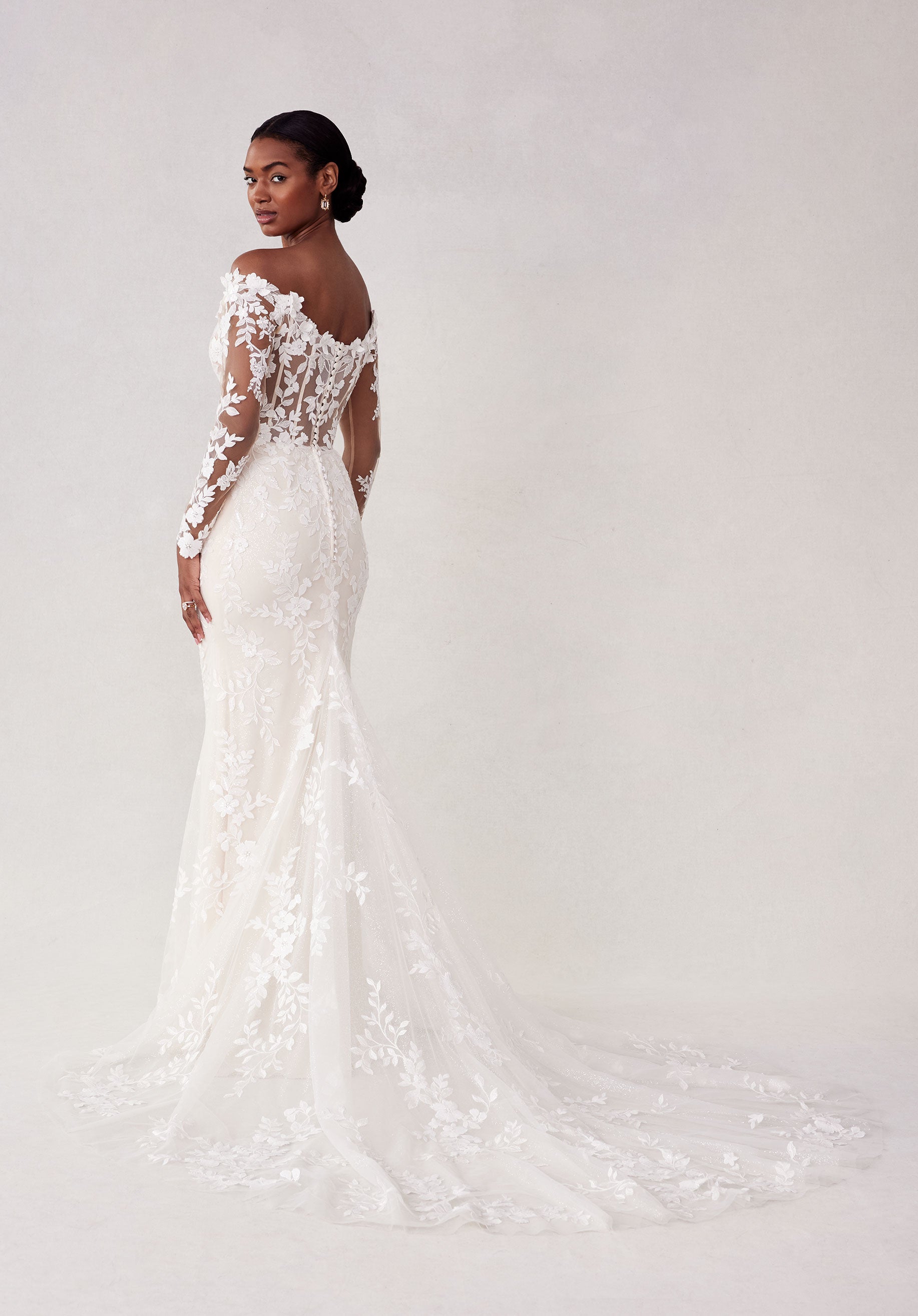 Woman wearing a white lace wedding dress on a plain background